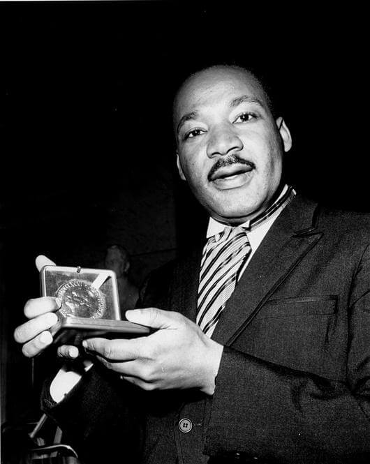The Rev. Dr. Martin Luther King, Jr. displays his 1964 Nobel Peace Prize medal in Oslo, Norway, December 10, 1964. The 35-year-old King was honored for promoting the principle of nonviolence in the civil rights movement.
